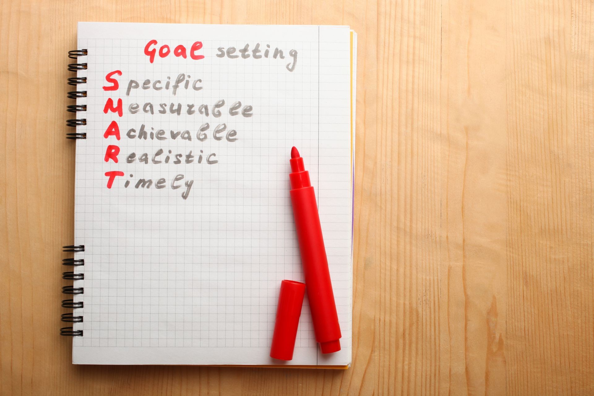 Notepad with goal setting on a wooden background.